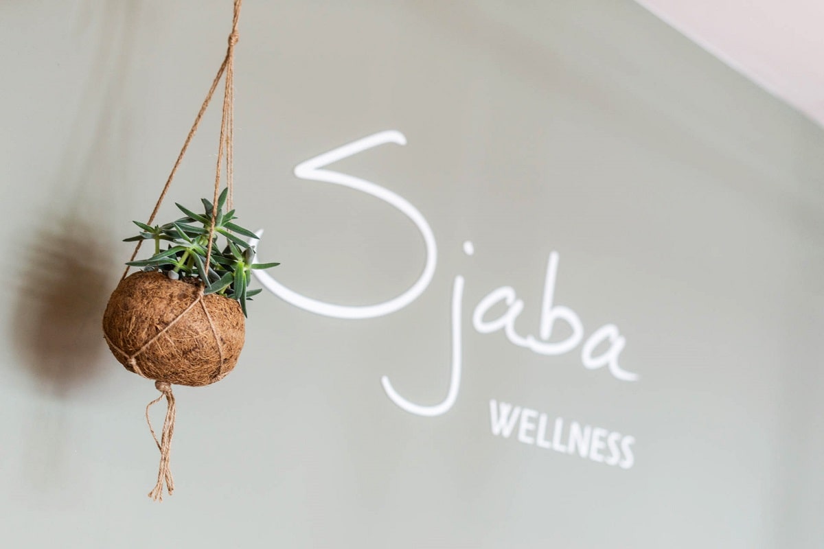 Logo van Sjaba wellness aan de muur achter de balie.
