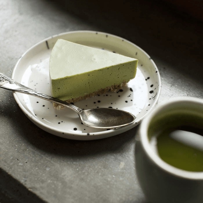 Cheesecake gemaakt met Moya Matcha, geserveerd op een schotel met een theelepel